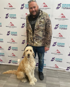 Man poses with newly adopted dog during Fall in Love Adoption Event.