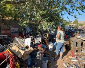 Rescuer stands in junk yard with piles of trash looking for injured kitten.