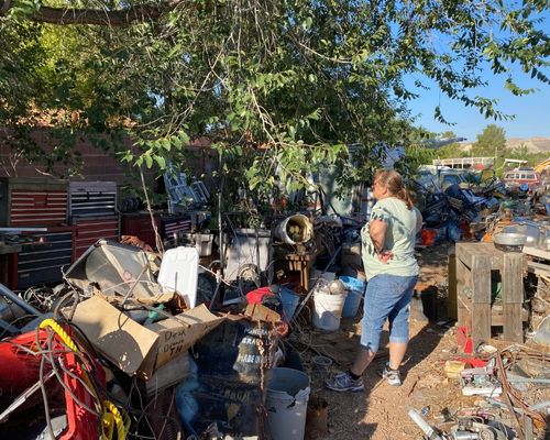 Rescuer stands in junk yard with piles of trash looking for injured kitten. 