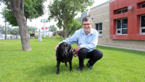 Vaughn Maurice poses in front of Humane Society of Utah building with a senior black lab.