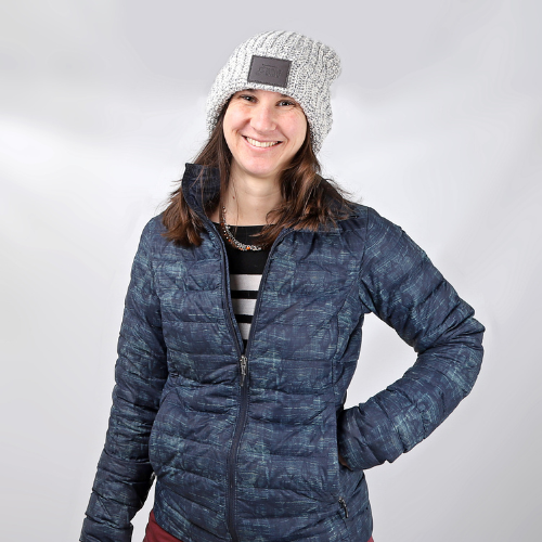 Young woman in a puffer jacket wears a grey winter hat with brown leather patch with Humane Society of Utah logo on it. 