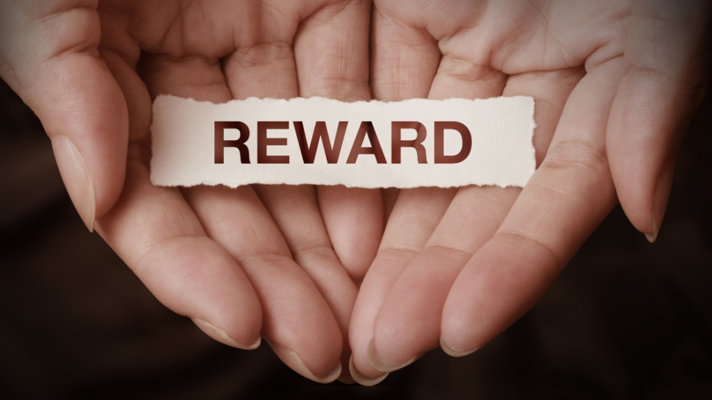 Woman's hands holding a piece of white paper that says reward on it.